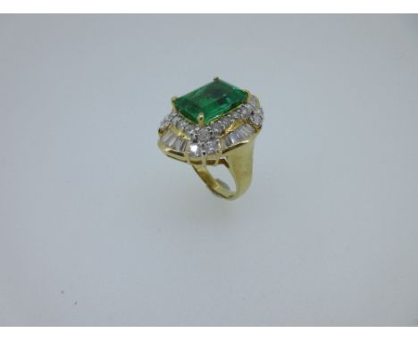 An impressive emerald and diamond ring, the step cut emerald, possibly of Colombian origin, a vivid green and markedly sparse