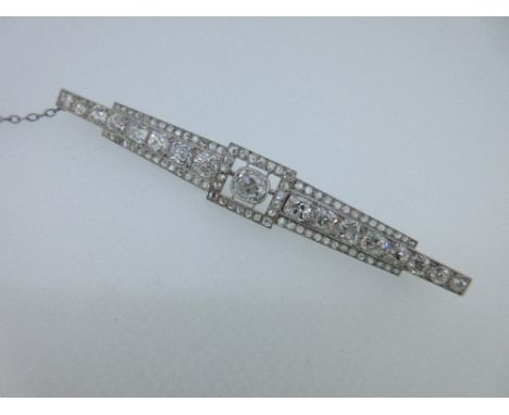 A French Art Deco diamond and platinum bar brooch, the central cushion shaped rub over set old cut diamond estimated to weigh