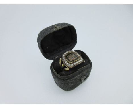 A Georgian mourning ring in contemporary ring box, the concave ring head with a central glazed panel of hair with overlaid in