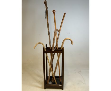 An early 20th century four section oak stick stand with metal tray to base also with a quantity of walking sticks and crooks.
