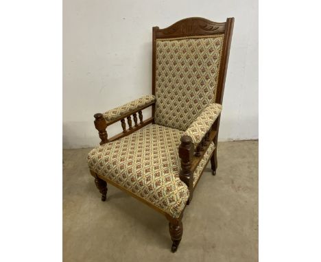 An early  20th century oak library chair with upholstery back, seat and arms, with turned details and brass and ceramic casto