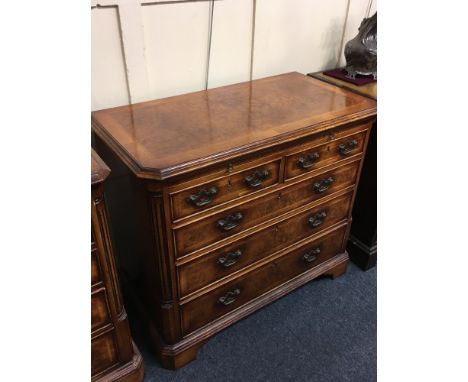 A George III style walnut feather banded chest with slide, three short drawers and two banks of three drawers,on bracket feet