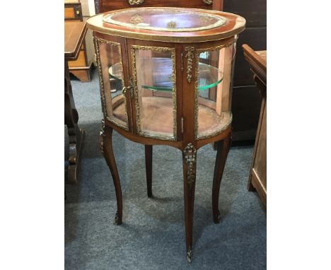 A late 19th century French gilt metal mounted oval vitrine, with two bowed glazed panel doors enclosing a glass shelf, on sle