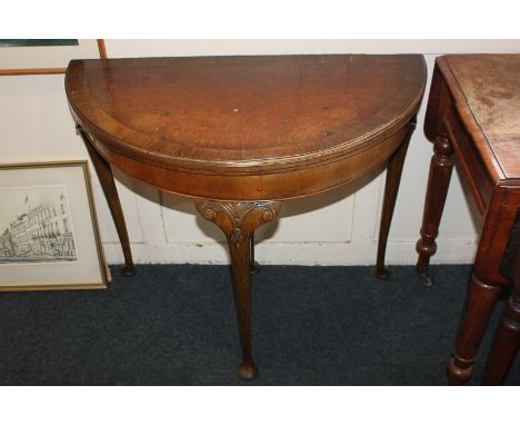 A 20th century walnut demi-lune card table, with cross banded fold-over top, on slender cabriole legs to pad feet, 80cm