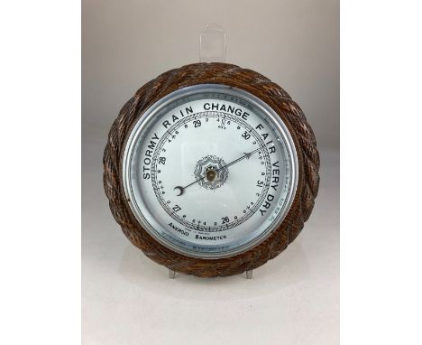A carved oak circular aneroid barometer, 23cm diameter