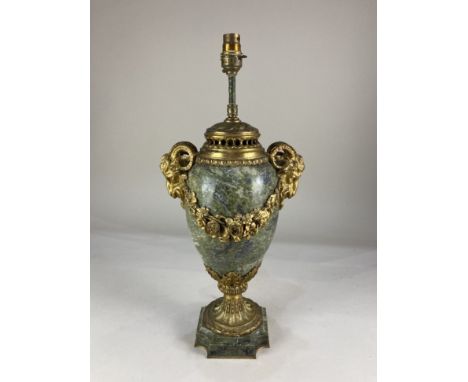 A gilt metal and green marble table lamp, with rams head mask lugs and floral swag design, on acanthus leaf support and squar