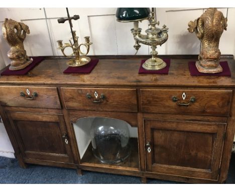 A George III oak dresser three drawers with drop handles and bone escutcheons above central pot shelf and two panelled cupboa