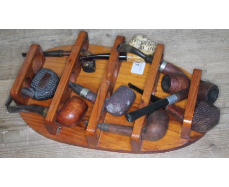 A collection of nine vintage pipes on a rack.  