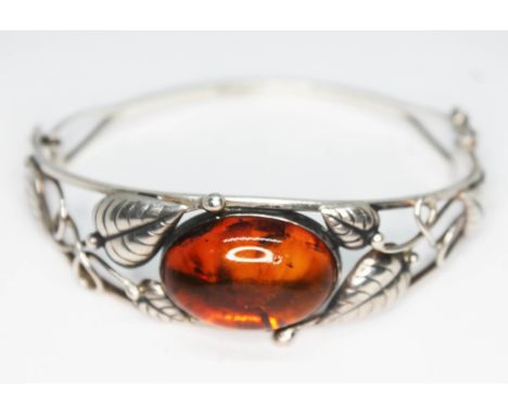 A Polish bangle of open floral design and set with an amber cabochon, marked '925' and Poland', diam. approx. 6cm.  