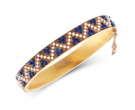 AN ANTIQUE LAPIS LAZULI AND PEARL BANGLE in yellow gold, in zig-zag design, set with seed pearls and cabochon lapis lazuli, F