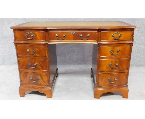 A Georgian style mahogany three section pedestal desk with a green tooled leather inset top and an arrangement of nine drawer