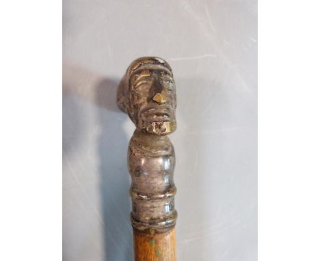 A walking cane with top in the form of an elderly man wearing a hat and silver ball topped swagger stick with relief eagle to