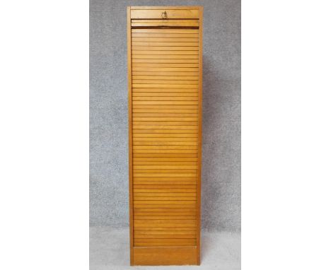 A mid 20th century light oak tall filing cabinet fitted tambour shutter and shelved interior. H.150 W.42 D.39cm 