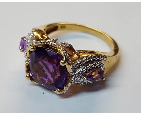 Silver gilt dress ring set with large square amethyst stone flanked by two teardrop shaped amethyst stones set in fancy silve