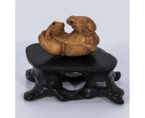 A small intricate hardwood netsuke of two frogs on stand