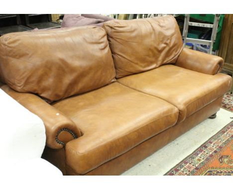 A modern brown leather three seat sofa raised on ringed and turned bun feet