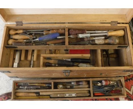 A wooden toolbox containing various hand tools to include chisels, level, drill bits etc, together with a brown plastic tray 
