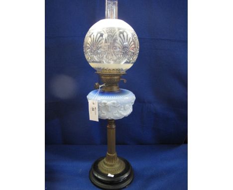 Brass double burner oil lamp with relief decorated ceramic reservoir on a brass pedestal with ceramic base. Etched glass shad