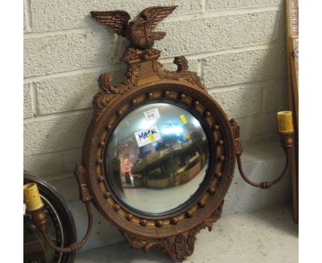 Gilt circular convex mirror with eagle pediment and candle holders. 