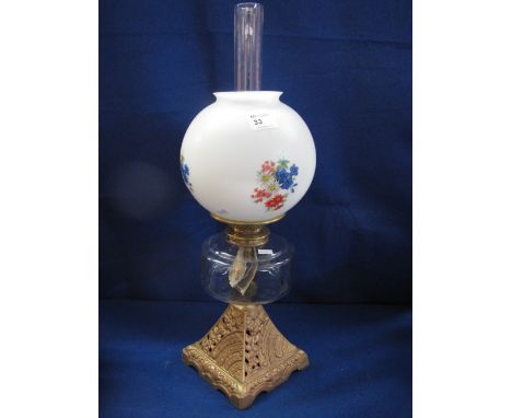 Early 20th century brass double burner oil lamp having clear glass reservoir on cast metal base, printed globular shade and c