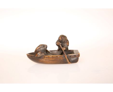 A JAPANESE WOOD NETSUKE, 19th Century, of two rabbits in a boat, each with inlaid eyes, signed Ikko to a rectangular reserve.