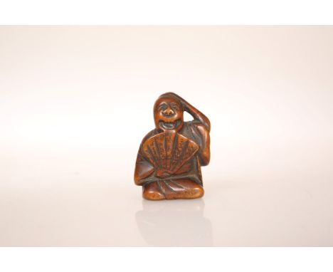 A JAPANESE BOXWOOD FIGURAL NETSUKE, carved as a man holding a fan. 48mm