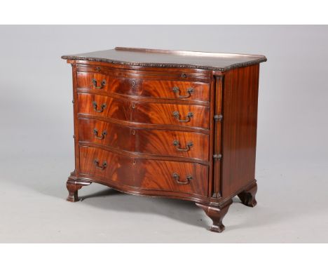 A GEORGE III STYLE MAHOGANY SERPENTINE CHEST OF DRAWERS, the top with foliate carved edge over a slide with four long graduat