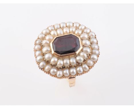 A LATE VICTORIAN GARNET AND PEARL RING, the emerald cut garnet collet set within a surround of eighteen uniform pearls, in tu