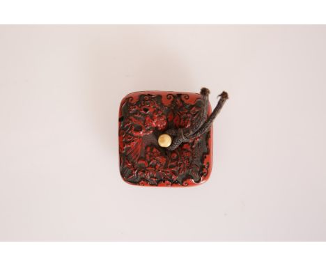 A JAPANESE RED LACQUER MANJU NETSUKE, 19th Century, of cushioned square shape with ivory peg. 40mm