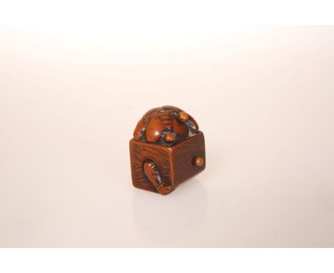 A JAPANESE BOXWOOD NETSUKE OF AN ONI, 19th Century, partially hidden in a wooden box in an attempt to avoid the scattering of
