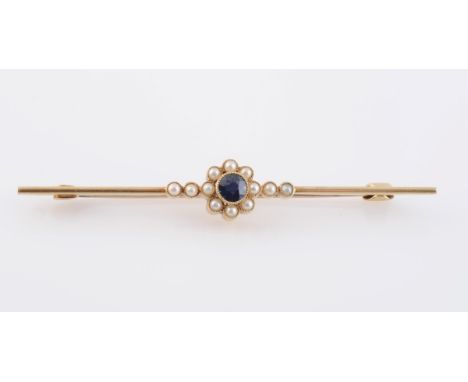 A SAPPHIRE AND SEED PEARL BROOCH, the round cut sapphire set within a surround of eight seed pearls to form a flowerhead shap