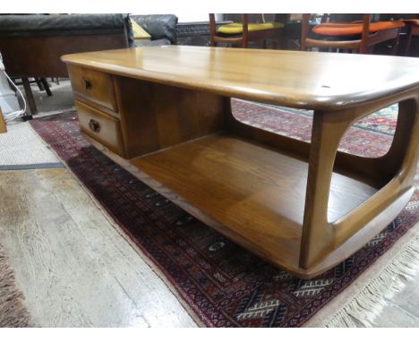 An Ercol dark blonde Windsor Minerva Coffee Table, with two drawers and open display section, raised on castors, W 125cm x D 