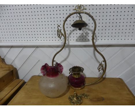 A Victorian hanging brass Oil Lamp, having a cranberry glass font and shade, one brass ornament broken but present and conver