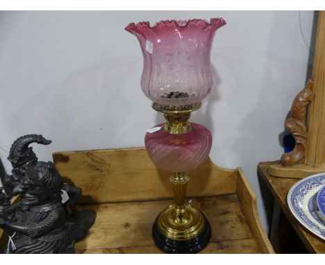 A Victorian brass and etched cranberry glass Oil Lamp, having a cranberry glass font and shade with etched floral decoration,