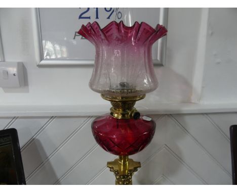 A Victorian Hinks patent brass column Oil Lamp, having a cut cranberry glass font and clear and cranberry etched shade, on st