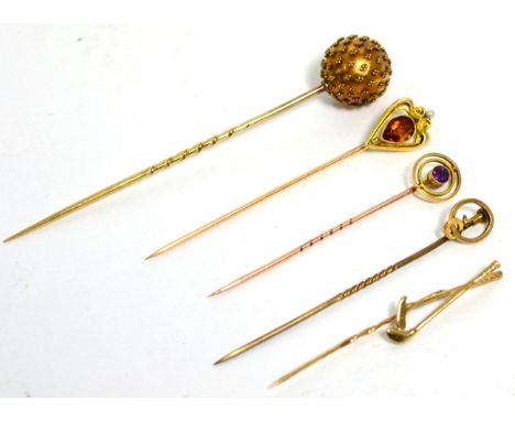 A citrine and seed pearl stickpin, stamped '14K', an amethyst stick pin, a golfing stick pin and another