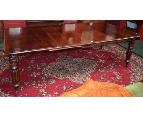 A William IV mahogany rounded rectangular wind-out dining table, moulded top above a deep frieze, turned and fluted legs carv