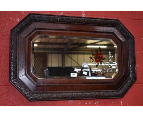 A 1930's/40's oak framed wall mirror, canted angels to rectangular etched and decorated plate, floral carving to frame