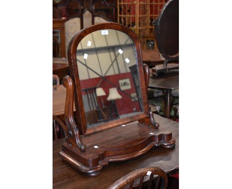 A Victorian dressing mirror, arched glass, shaped uprights, serpentine base, bun feet, circa 1860.