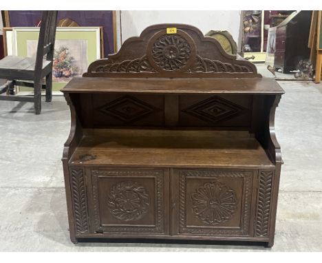 An oak mural cabinet enclosed by a pair of carved panel doors under a display shelf. 33" wide, c. 1900.