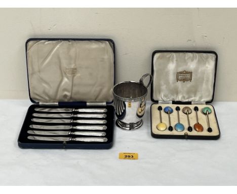 A cased set of six cake knives with loaded silver handles; a set of six enamel plated coffee spoons and a plated mug.