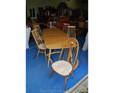 An Ercol extending table and four chairs and two carvers in slightly darker wood with swan motifs in the central splat.