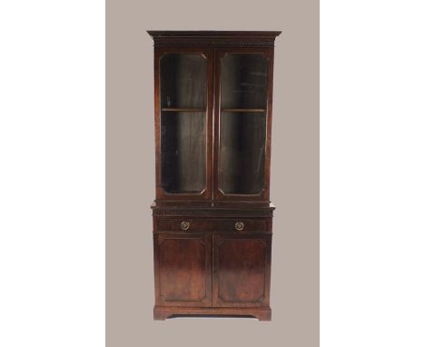 A 20th century Chippendale revival varnished cabinet bookcase with blind fret carved cornice above two glazed doors enclosing