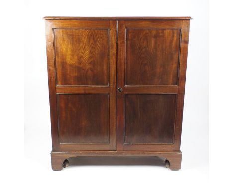 A two door mahogany hanging cabinet, 19th century, the rectangular top above two indented panel cupboard doors raised on shap