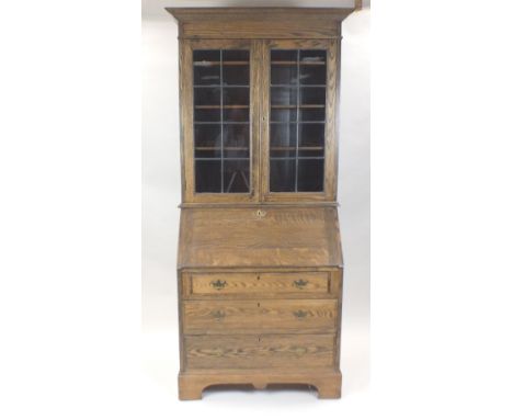An oak bureau bookcase the stepped cornice above two ribbed glazed doors enclosing adjustable shelves over a fall front and f
