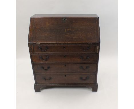 A George III oak bureau, late 18th/early 19th century the fall front enclosing a fitted interior of pigeon holes, short drawe