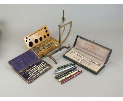 A box containing a selection of fountain pens, some with marbled finishes, box of weights (incomplete), drawing instruments (