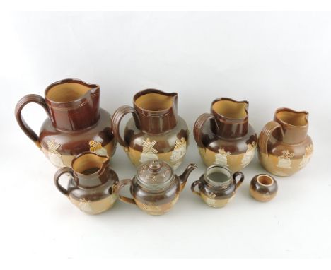 A harlequin set of five graduated salt glazed stoneware Doulton jugs, together with a silver mounted teapot, sucrier and inkw