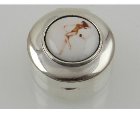 A novelty sterling silver circular pill box, the lid set with an enamel plaque depicting a young lady. D: 2.5cm