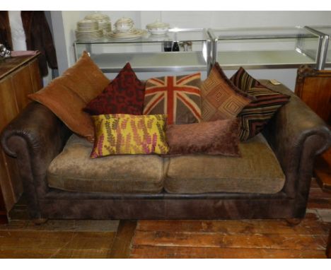 A Contemporary two seater leather sofa, having upholstered seats and various scatter cushions, raised on bun feet. 